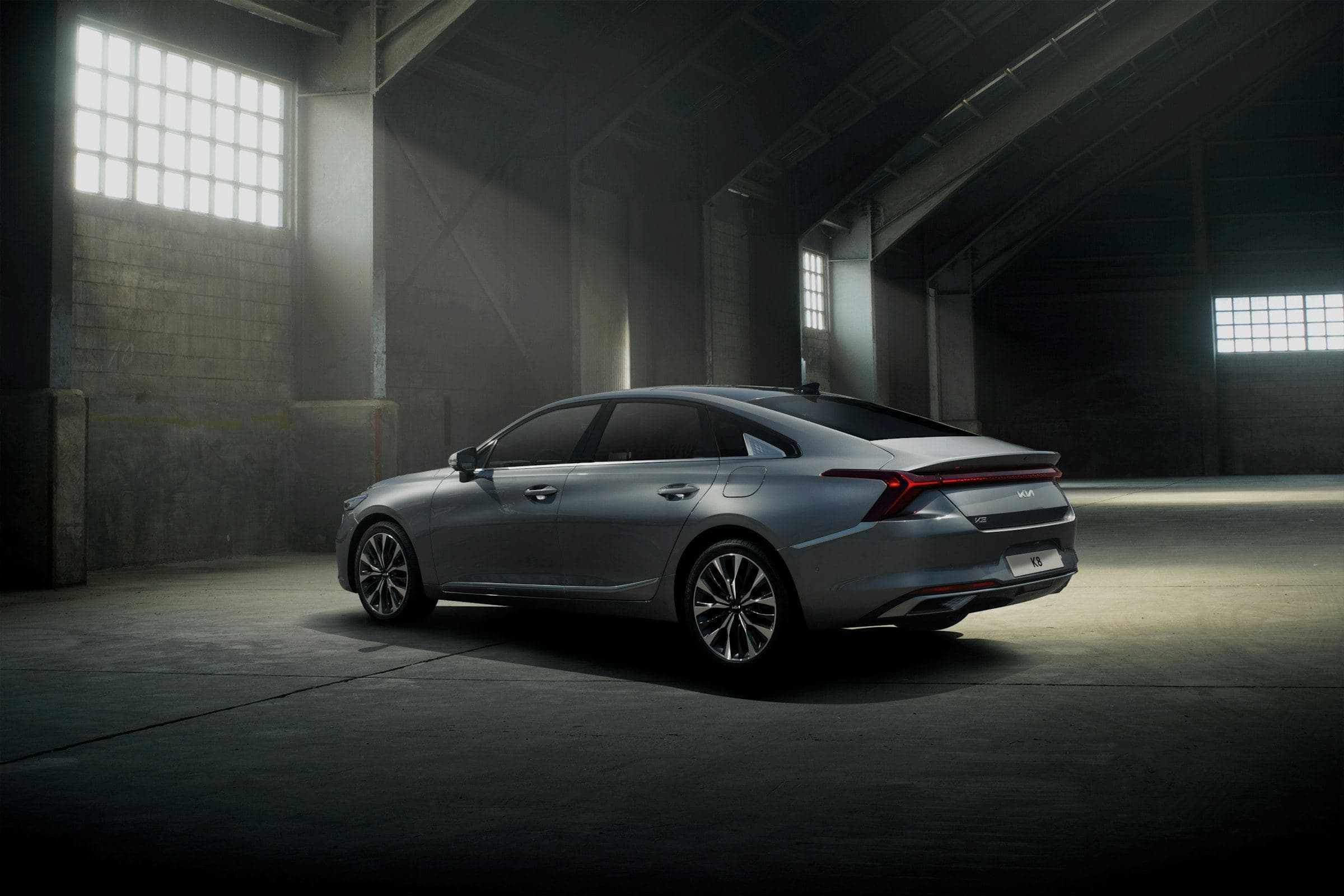 A silver sedan under dramatic light in a dark industrial garage