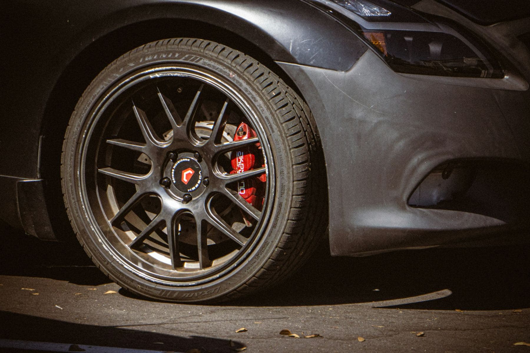 Close-up of a dark alloy wheel and performance tire with a red brake caliper